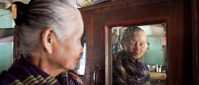 An elderly woman looks in the mirror in Myanmar