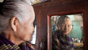 An elderly woman looks in the mirror in Myanmar
